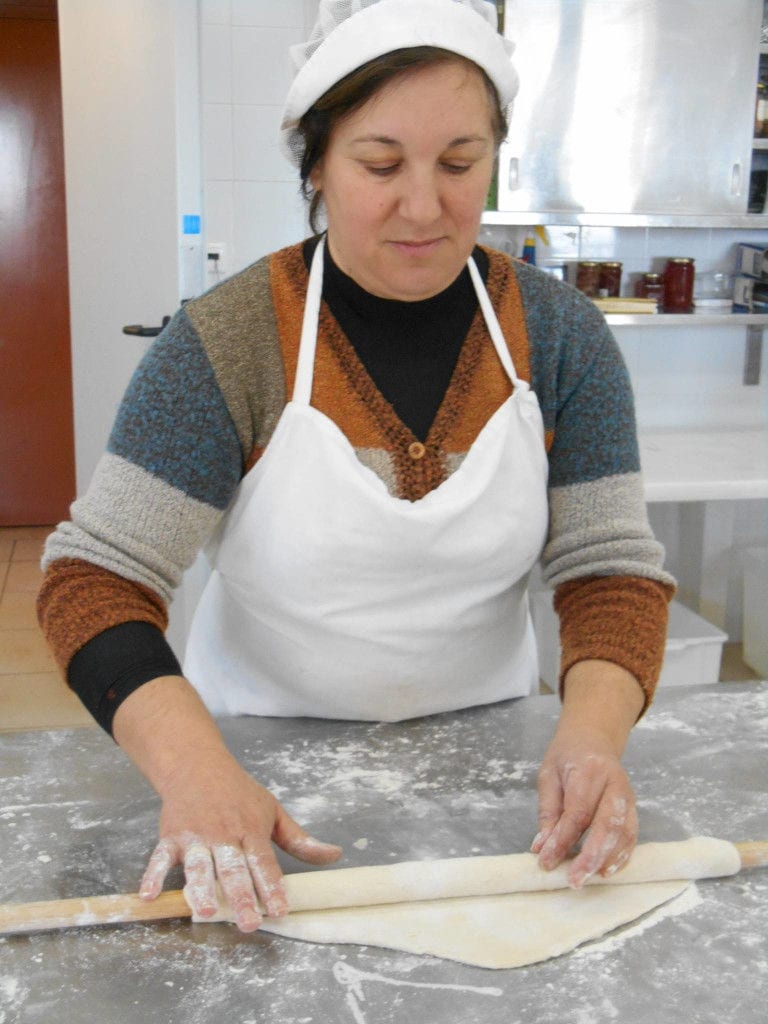 woman using wood dough paddles to laying filo dough at 'Agrotouristic Women's Cooperative of Mesotopos Lesvos'